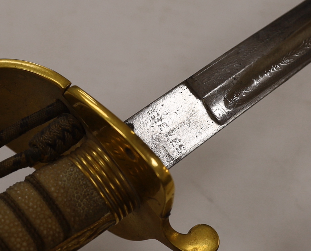 A World War I naval sword with folding guard engraved J.W. Collett R.N., regulation gilt hilt and scabbard mounts, the blade has been refinished and furniture regilded, with bullion dress knot, blade 78.5cm